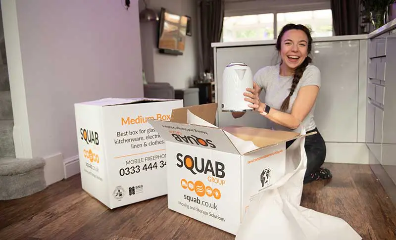 A woman happy lifting an item with two box